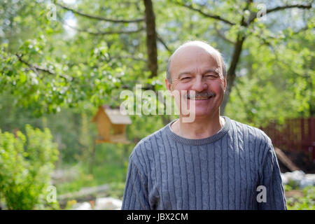 Reifer Mann sitzen im Garten in der Nähe von Apfelbaum im Land Stockfoto