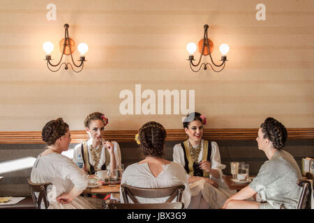 NOVI SAD, Serbien - 11. Juni 2017: Junge Frauen in einem traditionellen serbischen Kostüm mit einem Drink in einem Café Bild von 5 Mädchen mit einem drink Stockfoto