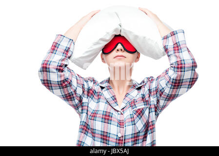 Eine junge Frau leidet an Schlaflosigkeit, ein Porträt mit einem Kissen auf dem Kopf Stockfoto