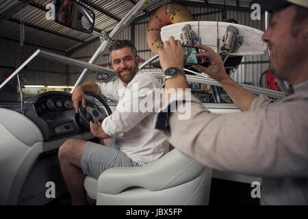 Mann fotografiert Kollegen im Boot bei Reparatur-Werkstatt Stockfoto