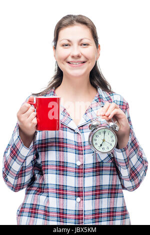 Brünette im Pyjama mit einer Tasse Kaffee und ein Wecker am Morgen, isoliert Stockfoto