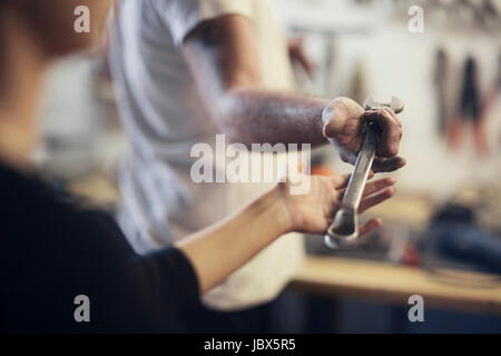 Über Schulter Blick des Mannes, die Übergabe der Schlüssel im Boot Reparatur Werkstatt Stockfoto