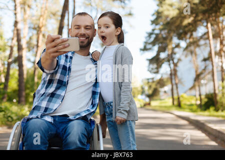 Erfreut Man neues Telefon in rechten Hand haltend Stockfoto