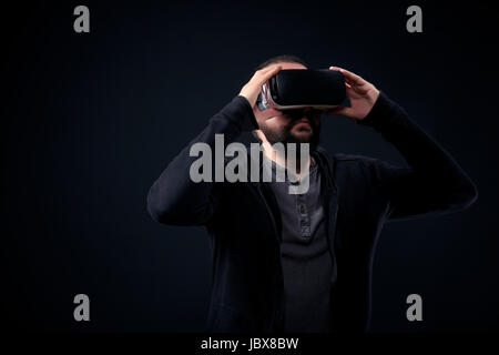 Junge Hipster, bärtigen Mann mit virtual-Reality-Brille. Schwarzem Hintergrund Studio VR Konzept Stockfoto