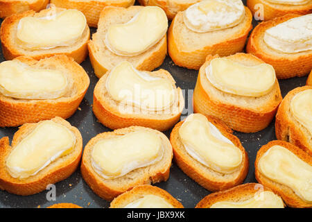 viele geröstete Brotscheiben mit geschmolzenem Ziegenkäse auf heiße Tablett Stockfoto