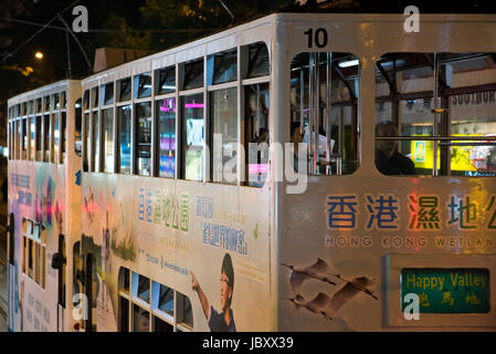 Horizontale Ansicht der traditionellen alten Straßenbahnen in der Nacht in Hong Kong, China. Stockfoto