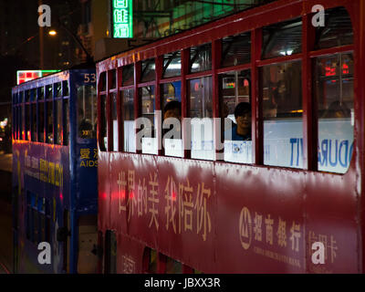 Horizontale Ansicht der traditionellen alten Straßenbahnen in der Nacht in Hong Kong, China. Stockfoto