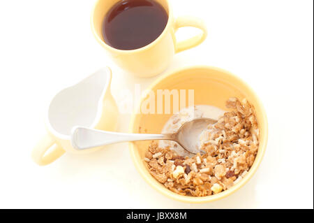 Erhöhte Ansicht einer gesunden Schüssel Müsli Müsli mit Milch und eine Tasse frisch gebrühten Kaffee serviert zum Frühstück auf einem weißen Hintergrund Stockfoto