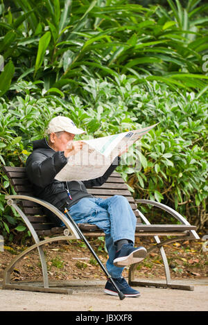 Vertikale Porträt eines alten Mannes lesen der Renn-Seiten in Hong Kong, China. Stockfoto