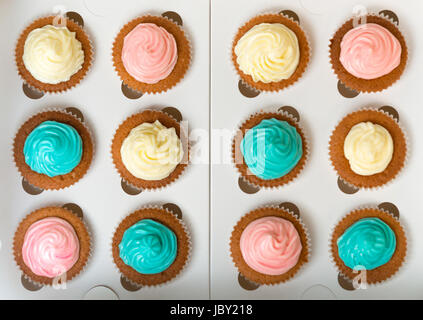 Blick von oben auf blau, rosa und weiße frisch gebackene Muffins mit Buttercreme Stockfoto