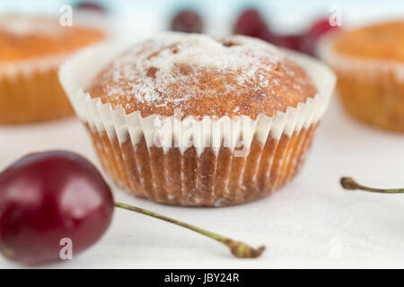 Nahaufnahme Foto des frisch gebackenen Muffin auf Tisch neben Kirsche Stockfoto