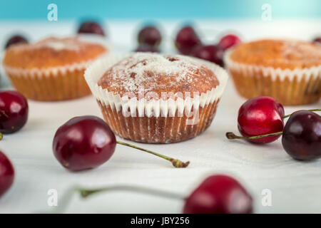 Makroaufnahme der frisch gebackene Muffins verziert von Kirschen auf Holztisch Stockfoto