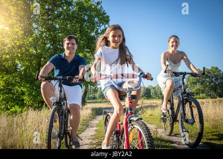 Glückliche fröhliche Familie mit Tochter Reiten Fahrräder in Wiese am sonnigen Tag Stockfoto