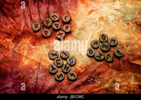 Set aus Holz Runen, eine antike Alphabet bekannt als das Futhark gliedern sich in die drei Aetts auf eine bunte Hand gefärbtes Gewebe mit kleinen funkelnden Perlen. Hinweis: Diese Runen wurden von den Fotografen gemacht. Stockfoto