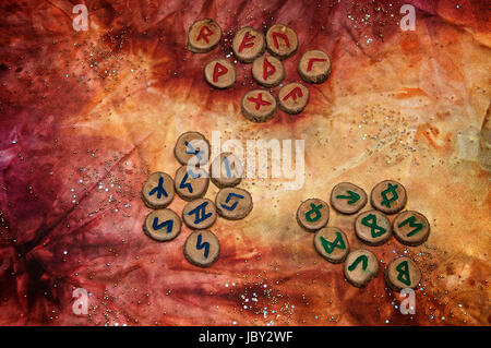 drei Sätze von hölzernen Wahrsagen Runen, einem alten Alphabet das Futhark genannt sind auf eine bunte Hand gefärbtes Gewebe mit kleinen funkelnden Perlen. Hinweis: Diese Runen wurden von den Fotografen gemacht. Stockfoto