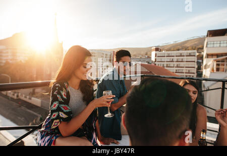 Gruppe von Freunden, die tolle Zeit zusammen auf Party. Junge Menschen genießen auf der Dachterrasse Party mit Getränken. Stockfoto