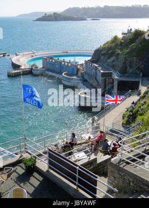 Menschen sitzen im Terrassencafé auf Plymouth Hacke Erfrischungen an sonnigen Sommertag neben Tinside Pool genießen. Sonne glitzern des klaren, blauen Meerwasser Stockfoto