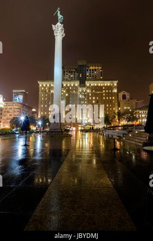 Eine Nacht-Blick auf den Union Square in der Innenstadt von San Francisco, California, Vereinigte Staaten von Amerika. Ein Wahrzeichen der Gegend mit einer Spalte mit einer Statue des Sieges hält einen Dreizack im Herzen des Stadtzentrums an der Spitze. Stockfoto