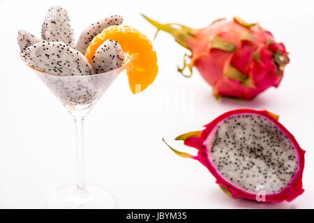 Das saftige Fruchtfleisch der Pitahaya Blanca in einem Glas präsentiert und dekoriert mit einer Mandarine Scheibe. Diese exotische Frucht wird auch Erdbeer Birne, Nanettika Obst oder Pitaya genannt. Stockfoto