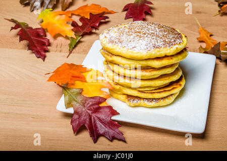 Frische Pfannkuchen mit Puderzucker mit Herbstlaub gekrönt Stockfoto