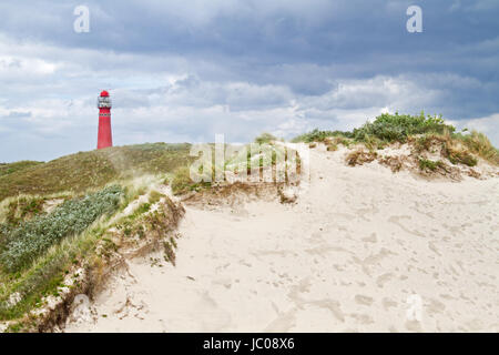 Roter Leuchtturm in den Dünen an einem windigen Tag, Sand in der Luft weht Stockfoto