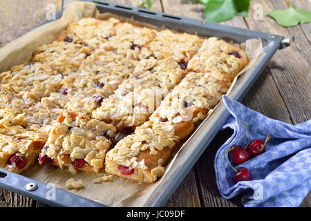 Hefekuchen mit frischen Kirschen und knusprige Mandel Karamell auf ein Backblech legen Stockfoto