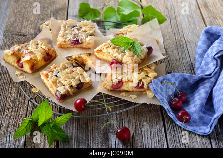 Österreichischen Frischhefe Kuchen mit Kirschen und knusprige Mandel Karamell serviert auf einem schäbigen Kühlregal Stockfoto