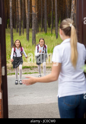 Junge Mutter, die ihre Töchter zu treffen, nach der Schule in Tür Stockfoto