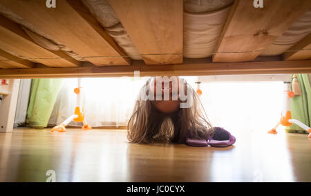 Porträt der schönen lächelnden Teenager-Mädchen Hausschuhe unter dem Bett suchen Stockfoto