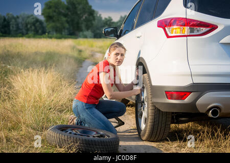 Schöne junge Frau Radwechsel Pkw auf der Landstraße gehen durch Feld Stockfoto