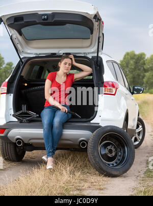 Junge verärgert Frau offenen Kofferraum sitzen und warten auf Hilfe, Reifenwechsel Stockfoto