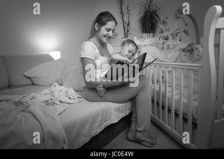 Schwarz / weiß Bild der jungen Mutter Lesebuch zu ihrem Baby Sohn vor dem Schlafengehen Stockfoto