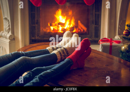 Closeup getönten Bild weiblicher und und Füße in Wolle Socken am Kamin im Chalet Erwärmung Stockfoto