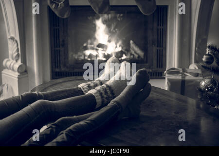 Closeup schwarz-weiß Bild der Familie Füße in Wollsocken Erwärmung am Kamin am Heiligabend Stockfoto