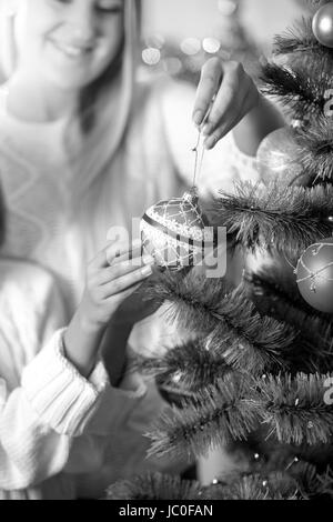 Closeup schwarz-weiß Bild Tochter helfende Mutter in dekorieren Weihnachtsbaum Stockfoto