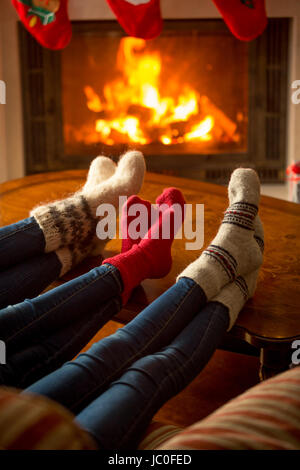 Drei Paar Füße in Wollsocken Erwärmung am brennenden Kamin im Haus Stockfoto