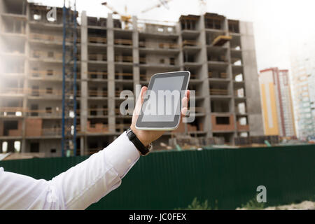 Nahaufnahme Bild der junge männliche Hand, die digital-Tablette mit Baustelle auf Hintergrund Stockfoto