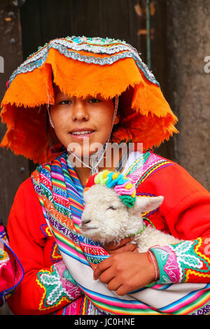 Junge Frau in Tracht Holding Lamm in der Straße von Cusco, Peru. Im Jahr 1983 war Cusco zum Weltkulturerbe von der UNESCO erklärt. Stockfoto