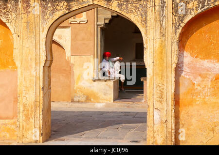 Lokale Mann sitzt im vierten Hof des Amber Fort, Rajasthan, Indien. Amber Fort ist die wichtigste touristische Attraktion in der Umgebung von Jaipur. Stockfoto