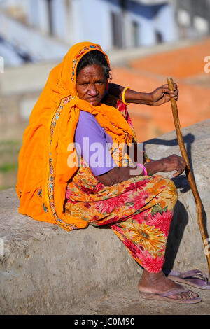 Frau im bunten Sari sitzt auf einer Steinmauer, Jaipur, Indien. Jaipur ist die Hauptstadt und größte Stadt im indischen Bundesstaat Rajasthan. Stockfoto