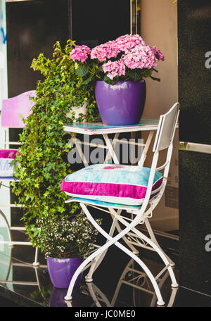 Dekorative Metallstuhl, Gartentisch und Pflanzen in Töpfen Stockfoto