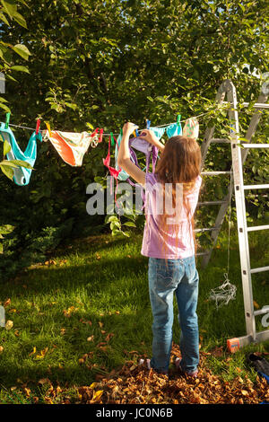 Junges Mädchen hängende Kleidung auf der Wäscheleine im Garten Stockfoto