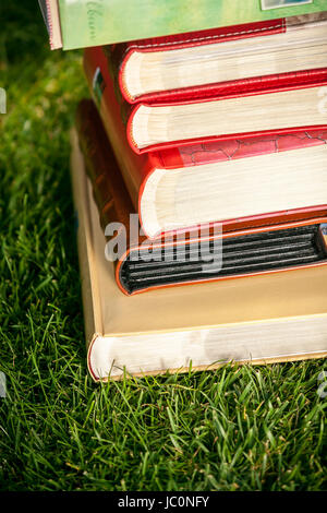 Nahaufnahme Foto von farbigen Bücherstapel liegen auf dem Rasen am sonnigen Tag Stockfoto