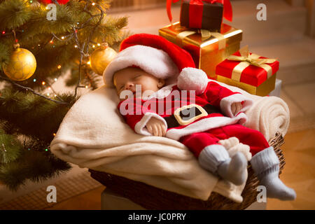 Kleine Baby Santa schläft unter Weihnachtsbaum mit präsentiert Stockfoto