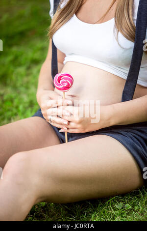 Nahaufnahme Foto junge schwangere Frau mit Lollipop am großen Bauch Stockfoto