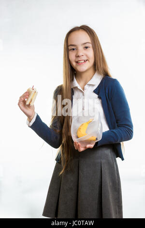 Glücklich lächelnde Mädchen, das Sandwich aus Lunchbox vor weißem Hintergrund Stockfoto