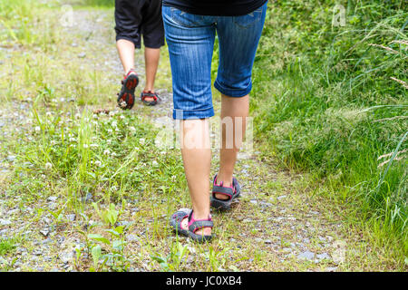 Frau zu Fuß mit Sohn Langlauf und Trail im Sommer Wald, Rückansicht Stockfoto