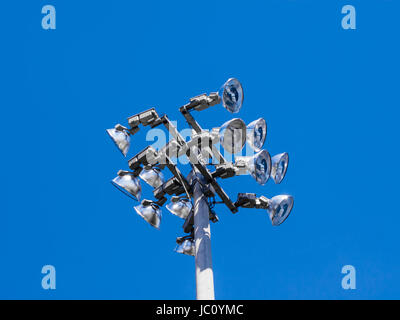 Spitze der industriellen Stadion Flutlicht mit zwölf Lampen am strahlend blauen Himmel. Stockfoto