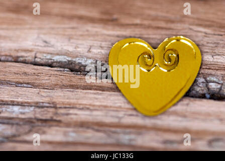 Goldenen Herzchen auf eine rissige Holzbrett liegend Stockfoto