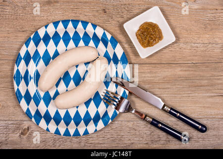 Teller Mit Besteck Und Weißwurst Und Senf Auf Einem Tisch aus Holz Stockfoto